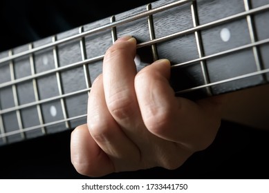 Bass guitar player hand close-up, concept of playing on electric guitar, live music and skill. Guitarist fingers on fretboard or fingerboard and frets. Lesson, recording and practice concept.