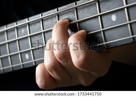 Bass guitar player hand close-up, concept of playing on electric guitar, live music and skill. Guitarist fingers on fretboard or fingerboard and frets. Lesson, recording and practice concept.