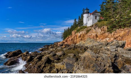 Bass Harbor Head Light - A wide-angle view of Bass Harbor Head Lighthouse standing on top of colorful seaside cliff against blue sky on a sunny Autumn morning. Acadia National Park, Maine, USA. - Powered by Shutterstock