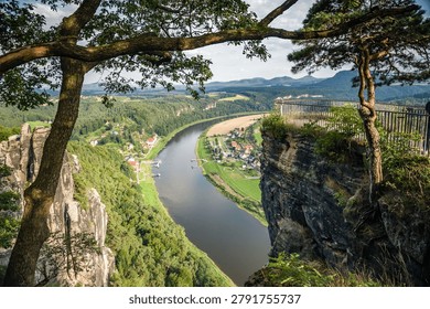 Bastei cliffs viewpoint looking down at Elbe river bend in Saxon Switzerland Germany, high rock canyon landscape panorama with green forest valley and village, famous european travel destination