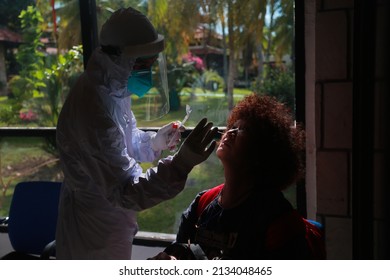 Batam, Kepulauan Riau - February 23, 2022 - Medical Staff With PPE Suit Test Covid-19 To First Asian Woman Tourist From Singapore By Nose Swab At Test Room At Singapura Harbour Batam. Not Noise