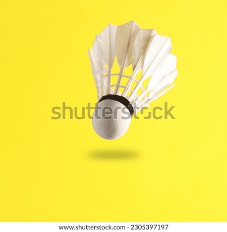Batbinton shuttlecock levitating on a yellow background with a shadow. minimalism photo