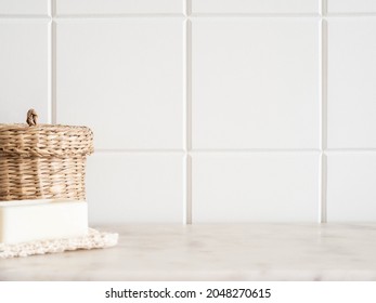Bath background front view with straw box and white soap on white marble shelf and wall tiles. Front view. Copy space