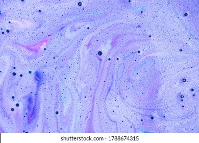 Bath bomb dissolves in blue, purple and pink rainbow colors in the water. Flat lay, top view, directly above. 