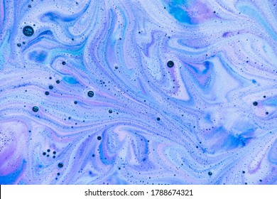 Bath bomb dissolves in blue, purple and pink colors in the water. Flat lay, top view, directly above. 