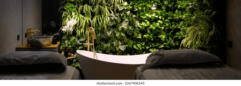 Bath in modern beauty salon, luxury bathroom interior in spa with vertical garden. Green plants wall, massage beds and bathtub in hotel. Concept of nature, landscaping, water, wellness, room. - Powered by Shutterstock