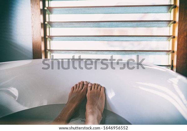 Bath soaking feet woman relaxing\
in hot bathtub water relaxation wellness foot\
therapy.