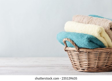  Bath towels of different colors in wicker basket on light background
