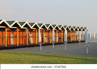 Bathing boxes on a beach in rows with some beach umbrellas