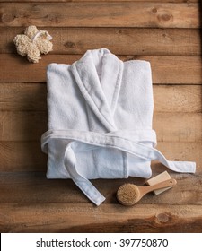bathrobe bath soap and loofah brush behind wooden table