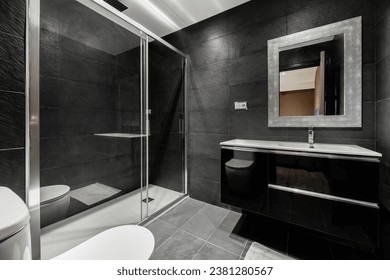Bathroom all tiled with black slate, glossy black wooden furniture, glass screen