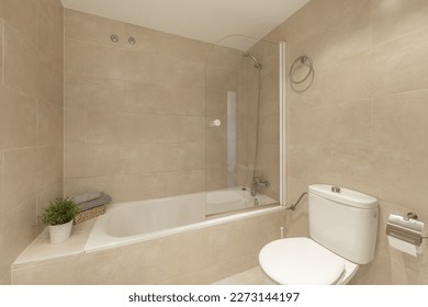 Cuarto de baño con bañera con pantalla plegable, baldosas de mármol y plantas decorativas