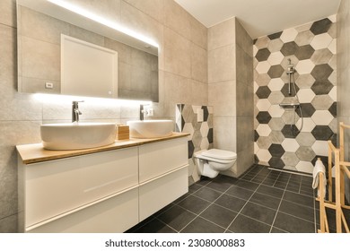 a bathroom with black and white hexagon tiles on the walls, wood counters and toilet in the corner