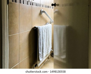 Bathroom Door Left Ajar And A Towel Hanging On A Radiator Reflects In The Door.