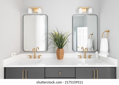 Bathroom a grey vanity, gold lights and faucets, and white marble countertop.