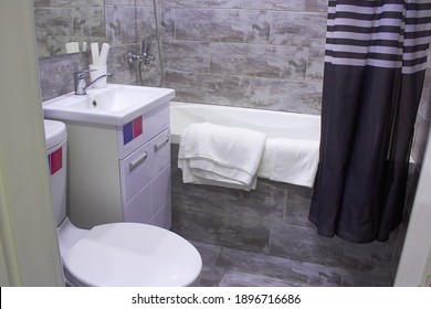 The bathroom has a modern design. In the photo, the toilet, bath, sink