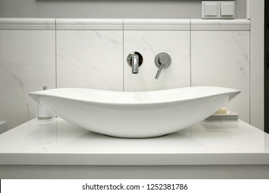 The bathroom has a modern style and marble tiles.