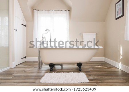 Bathroom interior, luxury modern bathroom design with roll top bathtub and a window in the background, UK