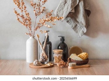 Bathroom interior still life. Decorative flowers, shampoo bottles, cotton buds, brushes, soap, towels on a wooden background. Minimalism interior       - Shutterstock ID 2025656699