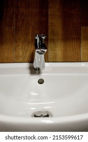 Bathroom Interior With White Sink And Faucet. Water Faucet And White Sink And Ceramic Tile With Imitation Brown Wood.