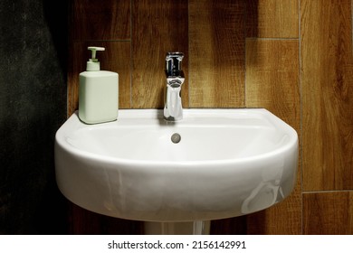 Bathroom Interior With White Sink And Faucet. Water Faucet And White Sink And Ceramic Tile With Imitation Brown Wood.