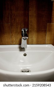 Bathroom Interior With White Sink And Faucet. Water Faucet And White Sink And Ceramic Tile With Imitation Brown Wood.