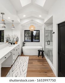 Bathroom In Luxury Home With Double Vanity, Bathtub, Mirror, Sinks, Shower, And Hardwood Floor