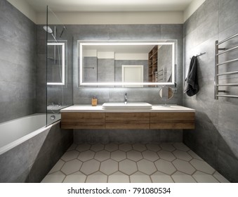 Bathroom in a modern style with gray and white tiles. There is a large mirror with luminous lamps, tabletop with wooden drawers and sink, bath with shower and glass partition, towel rack and a hanger.