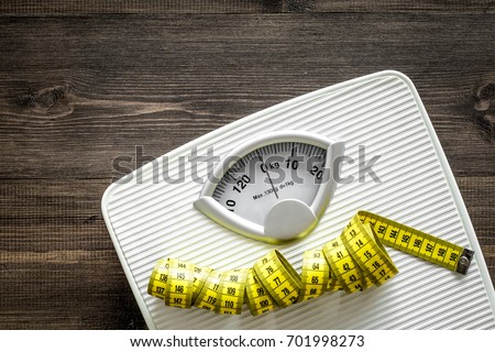 Bathroom scale and measuring tape on wooden background top view copyspace