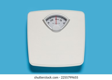 Bathroom scale on light blue background, top view