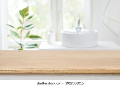 Bathroom sink near window with wooden table in front focus