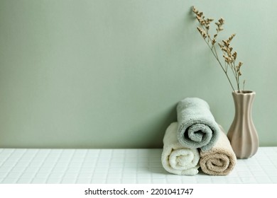 Bathroom towel and dry flower on white table. khaki green wall background. skin care and spa concept - Shutterstock ID 2201041747