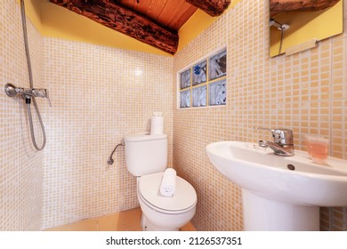 Bathroom with wall-mounted shower, white porcelain sink, square wall mirror and yellow mosaic tiles and exposed wooden beams