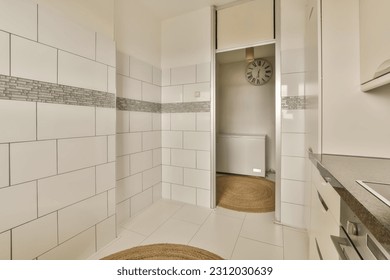 a bathroom with white tiles on the walls, and a clock in the middle part of the wall behind it - Shutterstock ID 2312030639