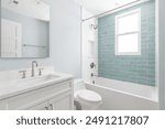 A bathroom with a white vanity cabinet, white marble countertop, and a shower with white and light blue subway tiles.