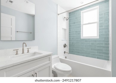 A bathroom with a white vanity cabinet, white marble countertop, and a shower with white and light blue subway tiles.