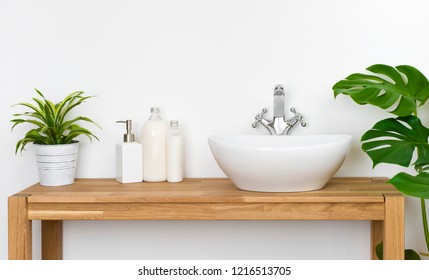 Bathroom wooden table with washbasin, faucet, plants and soap bottles - Powered by Shutterstock