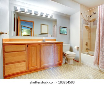 Bathroom With Wooden Vanity, Bath Tub With Tile Wall Trim And Light Pink Curtain