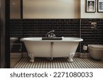 Bathtub, black and white bathroom design with freestanding white tub and black glossy tiles. This spa wellness inspired home interior design transforms your bathroom interior into self care space.