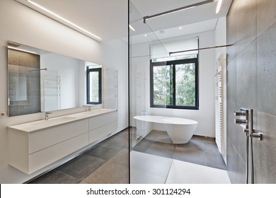 Bathtub in corian, Faucet and shower in tiled bathroom with windows towards garden