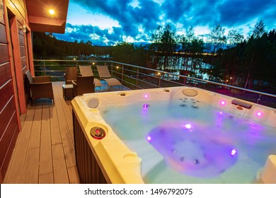 Bathtub with hydromassage on a sunset background. SPA treatments in the open air. Bosseyn with hydromassage on the balcony of the cottage. Hot tub on the terrace of the house. Spa treatments.
