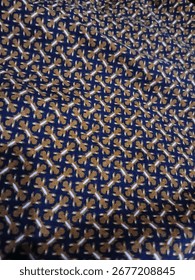 A Batik fabric with a dense, repeating pattern of small stylized figures in white and brown on a blue background.