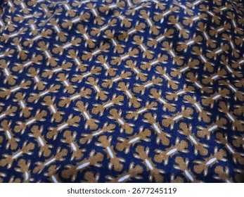 A Batik fabric with a dense, repeating pattern of small stylized figures in white and brown on a blue background.