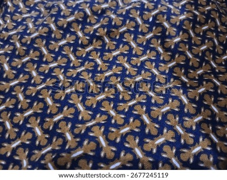 A Batik fabric with a dense, repeating pattern of small stylized figures in white and brown on a blue background.