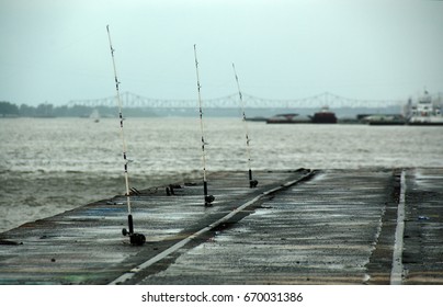 Baton Rouge, Louisiana, USA - 2019: Fishing Rods By The Mississippi River, With Part Of The Baton Rouge Coast In The Background.