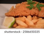 Battered fish and chips on a plate with garnish