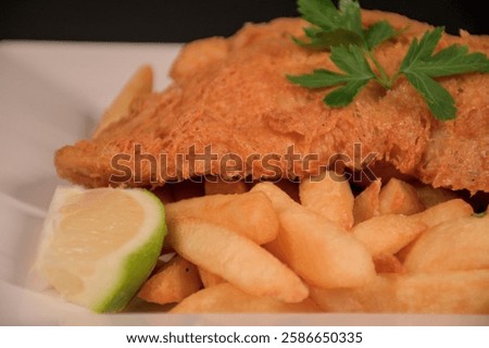 Battered fish and chips on a plate with garnish