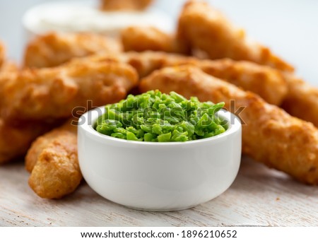 Battered Haddock fish, mini fingers with mashed peas, tartar sauce on white wooden board
