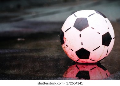 Battered Old Soccer Ball In A Winter Puddle.