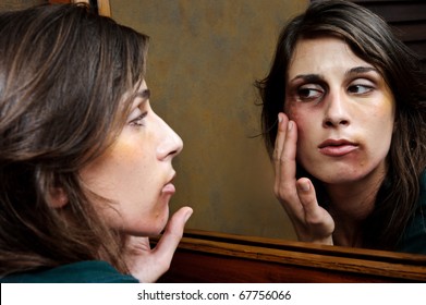 Battered woman checks the extent of her injuries in the bathroom mirror